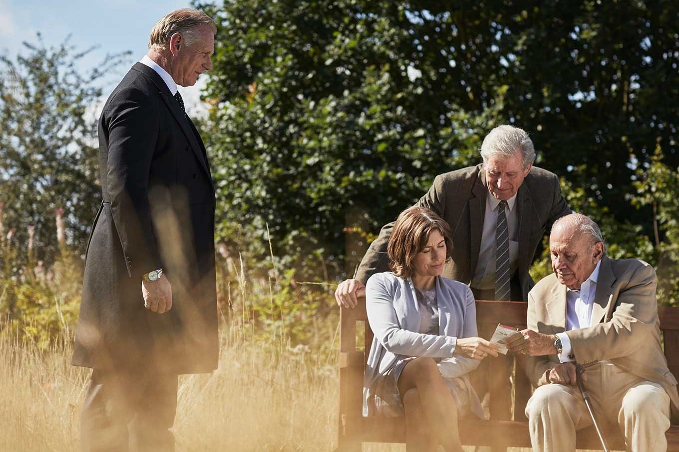 A funeral director speaks to a family who are sat on a bench